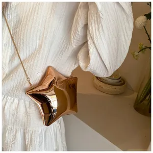 Borsa a tracolla a forma di stella oro rosa con catena su abito bianco