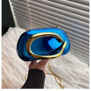 Detailed view of luxury blue acrylic evening bag with gold C-handle and metallic chain