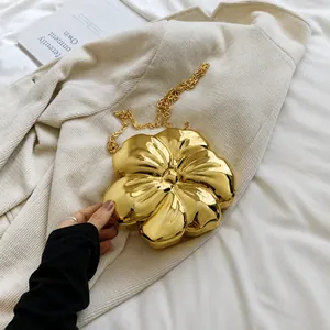 Detailed macro view of the gold flower-shaped metal mini bag and polished chain link