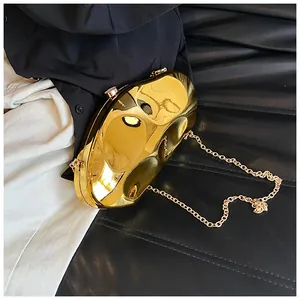Detail of a gold pebble-shaped acrylic clutch bag with a metallic finish and chain