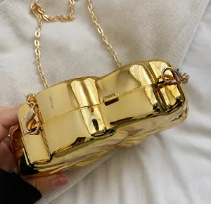 Close-up of golden metal lock and chain strap on a designer heart-shaped evening bag