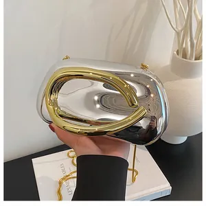 Close-up of pebble-shaped silver mirror clutch with chunky gold ring handle and chain