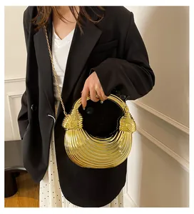 Detail of gold metal handbag featuring unique wavy textures and a round top handle