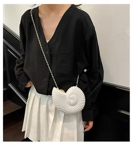 Sac bandoulière chic en forme de coquillage ivoire avec chaîne dorée sur mannequin