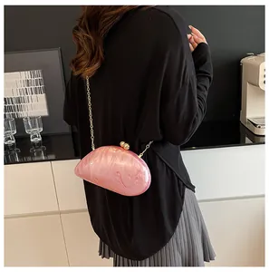 Detail of pink marble acrylic evening clutch featuring a gold orb clasp and fine chain