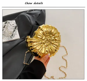 Nahaufnahme der goldenen Muschel-Clutch mit Metallic-Spiegelglanz und feiner Kette