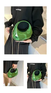 Détail d'une pochette en acrylique vert métallisé avec poignée évidée et chaîne dorée