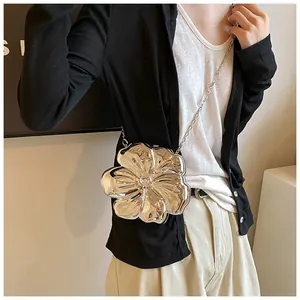 Dettaglio della borsa a fiore argento con catena indossata da una modella alla moda