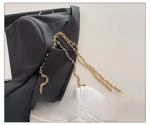 Gros plan sur la bandoulière chaîne dorée d'un sac coquillage en acrylique blanc