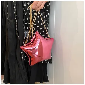 Detalle del bolso estrella rosa con acabado metálico y correa de cadena dorada
