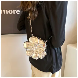 Dettaglio di una borsa a fiori in metallo argento indossata su un abito nero chic
