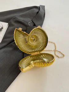 Détail de la pochette de soirée dorée en forme de coquillage avec texture métallique
