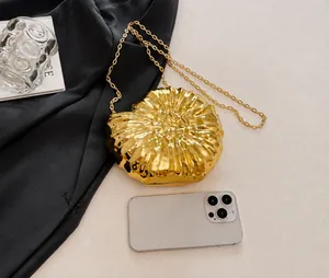 Detailansicht der goldenen Muschel-Clutch mit Kette und Smartphone zum Größenvergleich