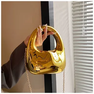 Detail der goldenen Spiegel-Acryltasche mit geometrischem Griff und feiner Metallkette