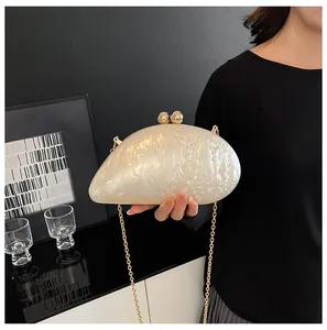 Detail of white acrylic marble evening clutch with gold sphere clasp and chain strap