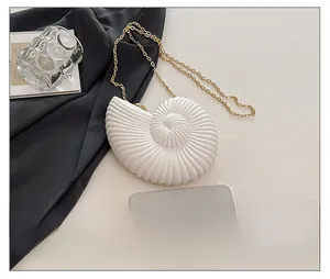 Détail macro de la pochette coquillage en acrylique blanc avec chaîne dorée et taille