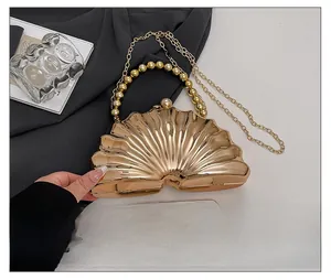 Shell shaped gold evening clutch with beaded handle and chain strap for size comparison