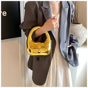 Goldene Acryl-Handtasche mit Spiegeleffekt und Kettenriemen an einem Model
