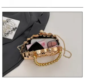 Detail view of gold shell evening bag capacity showing a smartphone and makeup items