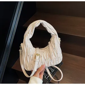 Detail of cream pleated handbag with crystal embellishments and gold hardware