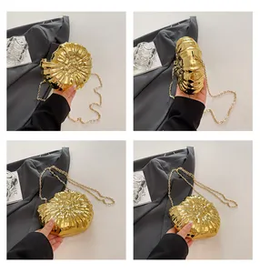 Detailaufnahme der goldenen Muschel-Abendtasche mit metallischer Nautilus-Struktur