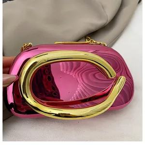 Detail of glossy metallic pink evening clutch featuring a large gold ring handle and chain