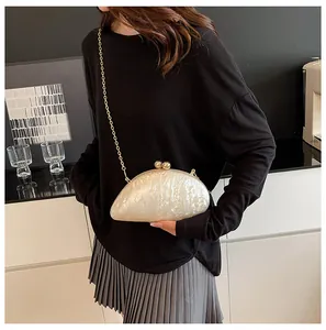 Elegant acrylic clutch with marble texture and gold chain on a minimalist model outfit