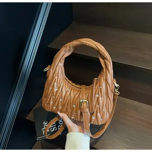 Close-up of caramel pleated quilted handbag with crystal studs and leather buckle strap