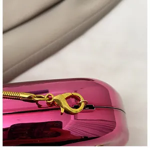Close-up of golden chain strap and lobster clasp on rose red metallic evening bag