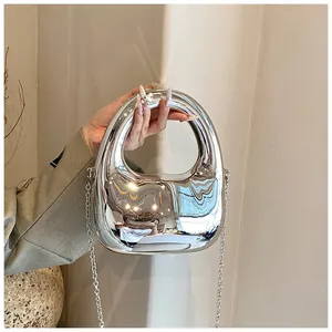 Nahaufnahme einer silbernen Acryl-Handtasche mit rundem Griff und feiner Metall-Kettenriemen
