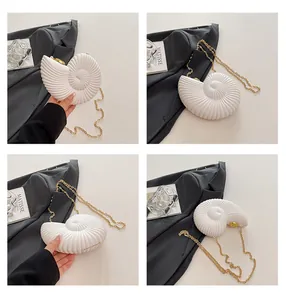 Détail de la pochette en acrylique blanc en forme de coquillage avec chaîne dorée