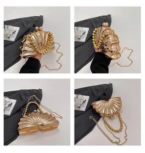 Detail of golden shell-shaped evening clutch bag with ripple texture and chain strap