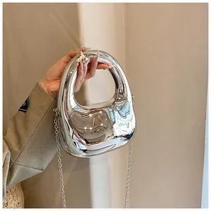 Detailaufnahme der glänzenden silbernen Acryl-Abendtasche mit ovalem Griff und Metallkette