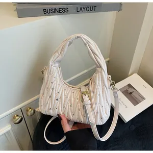 Detailed view of beige pleated handbag with crystal embellishments and golden hardware