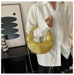 Detail of a golden metallic crescent handbag with wavy texture and gold chain strap
