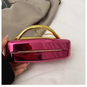 Close-up of metallic pink evening clutch bag with elegant gold curved handle detail