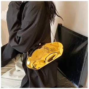 Close-up of a wavy gold acrylic evening bag with a metallic chain on a model
