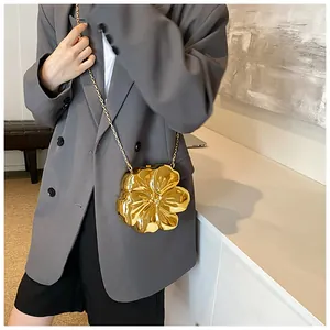 Dettaglio di una borsa a tracolla a forma di fiore dorato con catena sottile dorata
