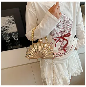 Detailed view of a gold evening clutch bag with beaded handle worn by a model