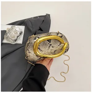 Detail van leer met slangenprint en gepolijste gouden C-vormige metalen versiering