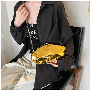 Detail of a gold metallic asymmetrical clutch with mirror finish and chain strap