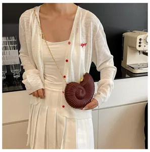 Vue détaillée du sac en acrylique bordeaux en forme de coquillage avec une chaîne dorée chic