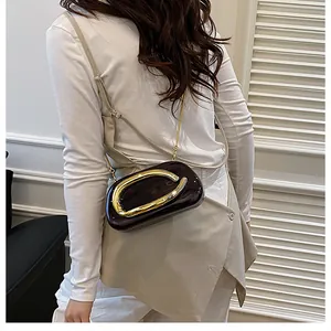 Detail shot of black patent leather evening bag with large gold metal buckle and chain