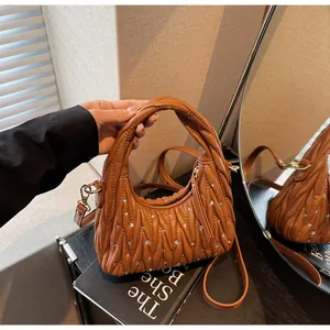 Close-up of brown quilted bag with crystal studs and golden metal hardware detail