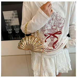 Detailed view of a gold shell-shaped acrylic evening clutch with beaded handle and chain