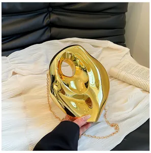 Close-up of a gold sculptural acrylic evening bag with a metallic mirror finish and chain