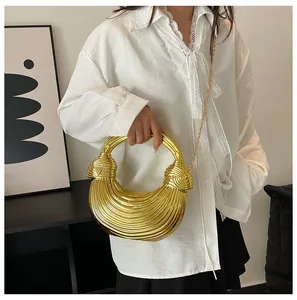 Detail of crescent gold woven bag with pleated texture and round handle on white shirt