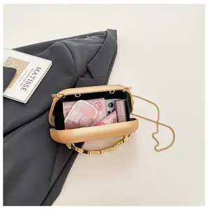 Internal view of gold hard-shell evening bag showing storage space for phone and makeup