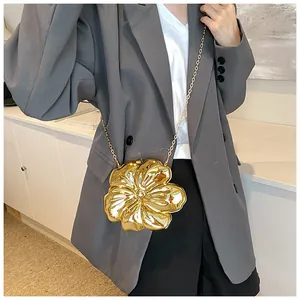 Dettaglio di una pochette da sera dorata a forma di fiore con sottile tracolla a catena
