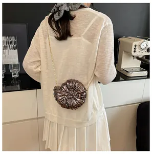 Detailansicht einer metallischen Clutch in Schneckenform mit goldener Kette am Model
